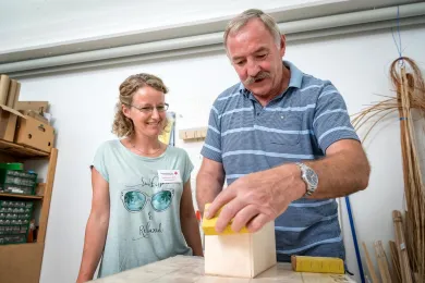 Ein Mann schleift mit Sandpapier eine Holzbox in der Ergotherapie Stans