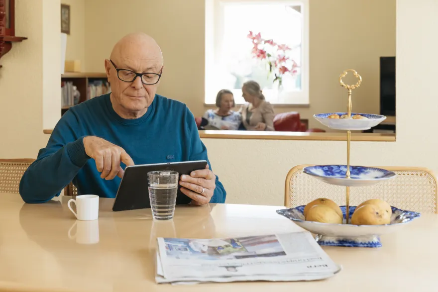 Mann mit Tablet am Küchentisch